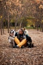 Very smiling young woman sitting in the autumn park with two dogs Royalty Free Stock Photo