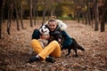 Very smiling young woman sitting in the autumn park with two dogs Royalty Free Stock Photo