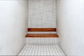 The very sober interior of a prison cell: bare tiled walls and a wooden bench Royalty Free Stock Photo
