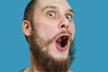 Very surprised scared funny face of a bearded guy with open mouth and big eyes on an isolated background