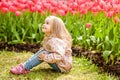 Very sweet beautiful blonde girl in a pink coat sitting near the Royalty Free Stock Photo