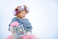 Very sweet beautiful little smiling girl child in pink skirt and mittens, white pullover, gray scarf and floral wreath with old Royalty Free Stock Photo