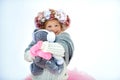 Very sweet beautiful little smiling girl child in pink skirt and mittens, white pullover, gray scarf and floral wreath with old Royalty Free Stock Photo