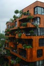 A very tall wooden modern building covered in numerous plants