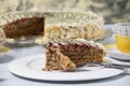 Very tasty piece of cake cut with a fork on a white plate and a cup of coffee in yellow on a light wooden table. The process of Royalty Free Stock Photo