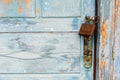 A very worn and battered old blue door locked with a rusty Royalty Free Stock Photo