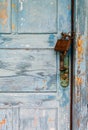 A very worn and battered old blue door locked with a rusty Royalty Free Stock Photo