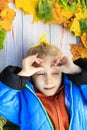 Very yellow. funny girl lying on a fallen leaf. blue jacket. eye squeezed. close-up