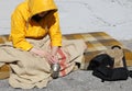 Young homeless man with a yellow hood on a filthy mattress while begging on the sidewalk