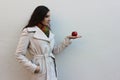 Woman in a coat holds and look a red juicy apple