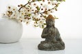Vesak, Wesak, Buddha birthday. Buddha statue with blossoming cherry on white background. Spa ritual. Mental health and