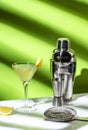 Vesper cocktail drink with dry gin, vodka, aperitif, lemon zest and ice in martini glass. Light green background, hard light, Royalty Free Stock Photo