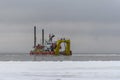 Vessel engaged in dredging at sunset time. Hopper dredger working at sea. Ship excavating material from a water environment