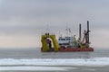 Vessel engaged in dredging at sunset time. Hopper dredger working at sea. Ship excavating material from a water environment