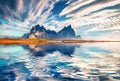 Vestrahorn Batman Mountain reflected in calm waters of Atlantic ocean.