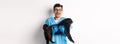 Vet clinic concept. Happy male doctor veterinarian holding cute black pug dog, smiling at camera, white background Royalty Free Stock Photo