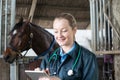 Female Vet With Digital Tablet Examining Horse In Stable Royalty Free Stock Photo