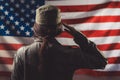 Veterans Day, Memorial Day, Independence Day. A female soldier saluting against the background of the American flag. Rear view. Royalty Free Stock Photo