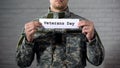 Veterans day word written on sign in male soldier hands, gratitude and respect