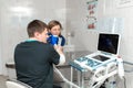 A veterinarian does an ultrasound of the dog`s eye in the office. Assistant helps keep the dog when the doctor is a veterinarian
