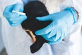 Veterinarian specialist holding small black dog and applying drops at the withers, medicine from parasites, ticks, worms and fleas