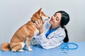 Veterinarian woman wearing uniform at the clinic, hugging dog with love Royalty Free Stock Photo