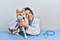 Veterinarian woman wearing uniform at the clinic, hugging dog with love Royalty Free Stock Photo