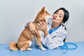 Veterinarian woman wearing uniform at the clinic, hugging dog with love Royalty Free Stock Photo