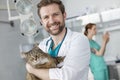 Portrait of smiling doctor carrying cat while standing at veterinary clinic