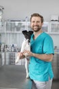 Portrait of smiling veterinary doctor standing with dog at clinic