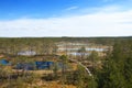 Vew of Viru Raba bog in Estonia with several small blue lakes and small coniferous forest with a wooden walkway passing through