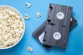 VHS tapes and popcorn on blue background. Royalty Free Stock Photo