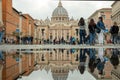 Via della Conciliazione, St. Peter`s Basilica, Vatican, people walk, reflection of the Cathedral in a puddle. Royalty Free Stock Photo