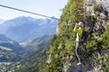 Via ferrata climbing, woman in harness crossing rope bridge in the mountains Royalty Free Stock Photo