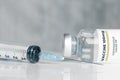 Vial of coronavirus Covid-19 vaccine and an hypodermic syringe on a white reflective surface Royalty Free Stock Photo