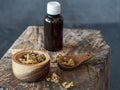 Vial of propolis, wooden bowl and spoon of propolis granules on piece of wood. Royalty Free Stock Photo