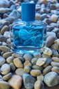 Vial of Puma brand fragrance in blue color on small sea rocks