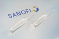 Vials of liquid on a white table and the logo of a large pharmaceutical company Sanofi