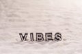 Vibes word on white sand