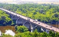 Vibrant aerial view of a river arch automobile stone bridge with moving cars in summer