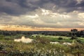 Vibrant beautiful rural landscape with dramatic sky and river during sunrise in early morning