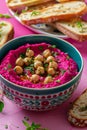 Vibrant beetroot hummus garnished with chickpeas and herbs in a colorful bowl Royalty Free Stock Photo