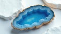 A vibrant blue agate geode, delicately framed in gold, rests elegantly on a pristine white surface, creating a sophisticated and Royalty Free Stock Photo