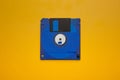 Vibrant blue 3.5-inch floppy disk centered on a bright yellow, contrasting back Royalty Free Stock Photo