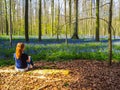 Young woman enjoying the vibrant blue and purple carpet of bluebells