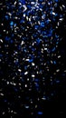 Vibrant blue and silver metallic confetti falling isolated on a dark black background Royalty Free Stock Photo