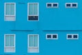 Vibrant blue wall of a building with several white-framed windows Royalty Free Stock Photo