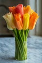 Vibrant Bouquet of Fresh Orange and Yellow Tulips in a Clear Vase on a Marble Surface