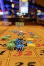Vibrant casino table with roulette in motion, with casino chips, tokens, the hand of croupier, dollar money and a group Royalty Free Stock Photo