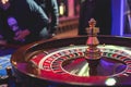 Vibrant casino table with roulette in motion, with casino chips, tokens, the hand of croupier, dollar bill money and a group of Royalty Free Stock Photo